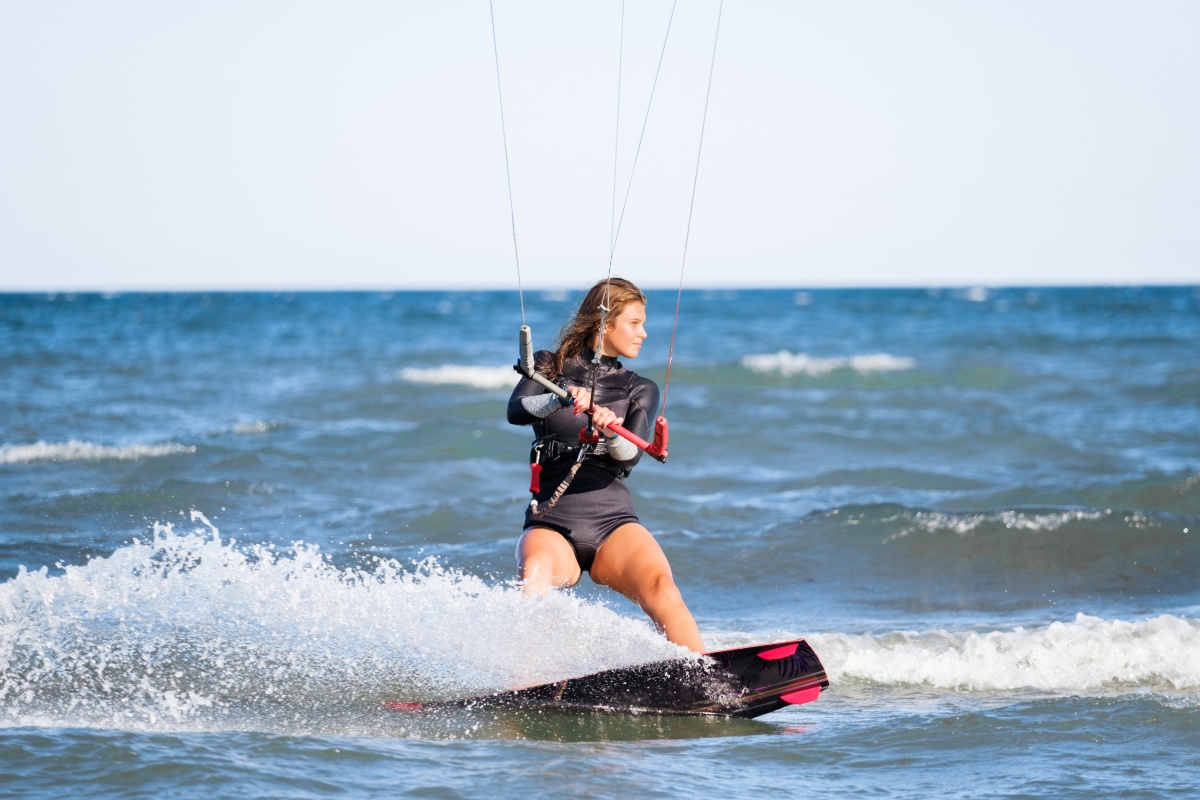 Frau in Neoprenanzug beim Kitesurfen auf dem Meer.