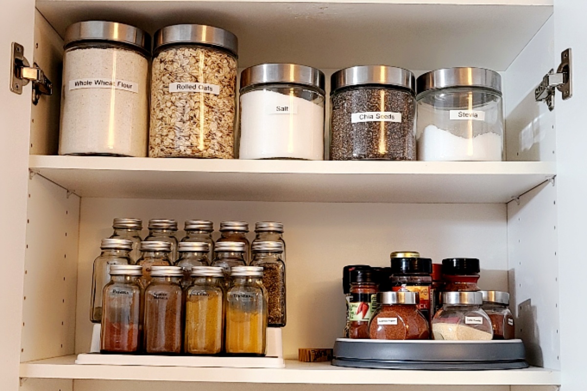 Ein Vorratsschrank mit trockenen Lebensmitteln und Gewürzen in Gläsern.