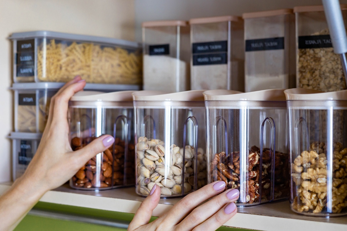 Hände greifen nach einem Vorratsbehälter mit Nüssen.