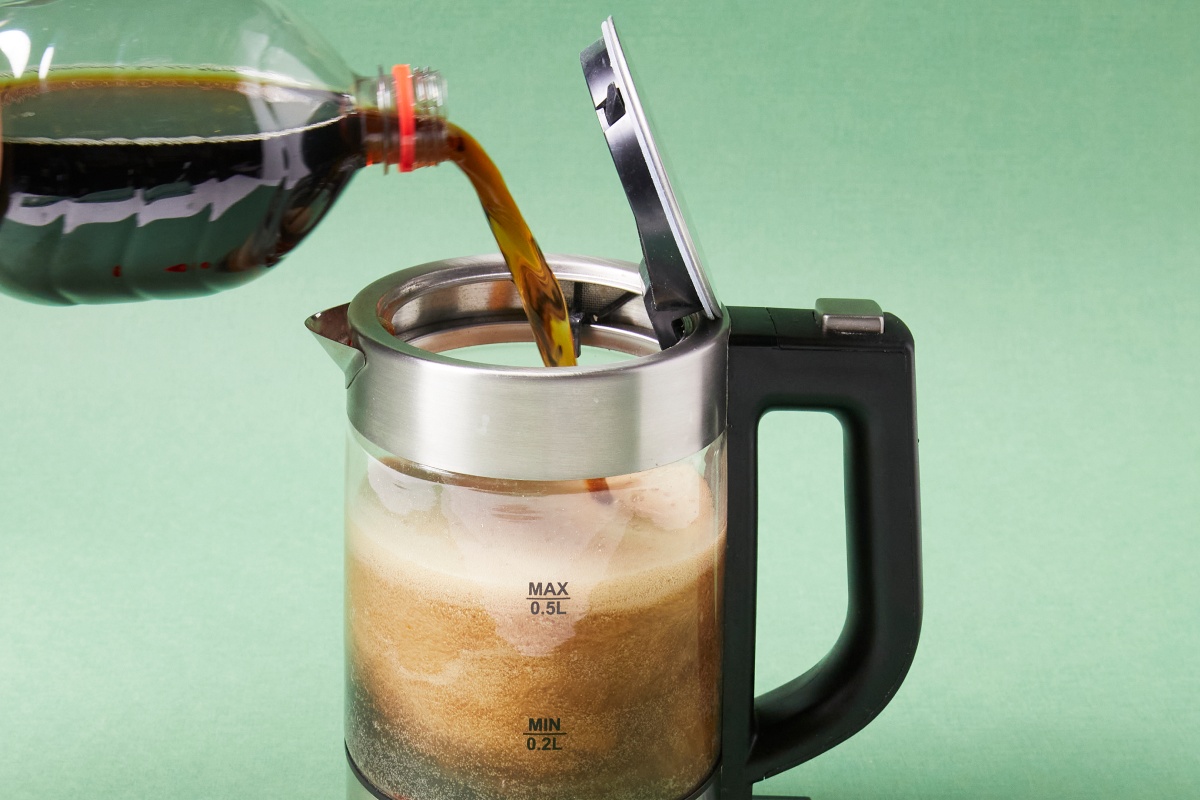 Ein Wasserkocher wird gerade mit Cola befüllt.
