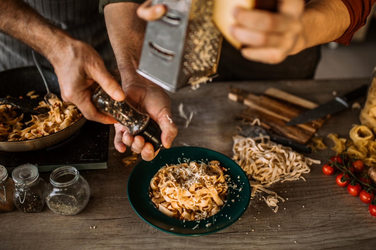 Zwei Personen bereiten zusammen ein schlichtes Pasta Gericht mit ausgewogenen Zutaten zu.