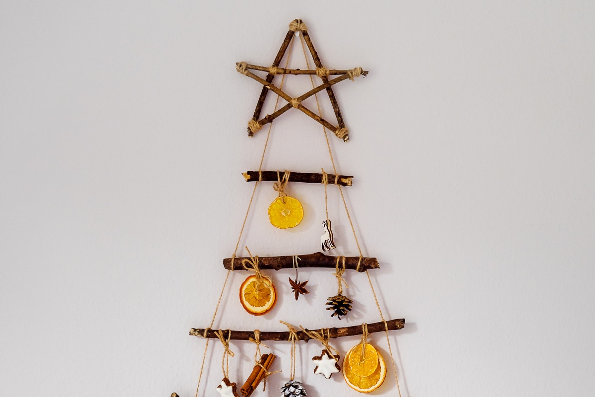 Weihnachtsbaum-Wanddekoration aus Ästen, mit getrockneten Orangenscheiben, Sternanis und Tannenzapfen verziert.