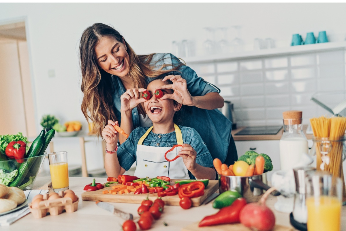 Mutter spielt beim Kochen mit Kind.