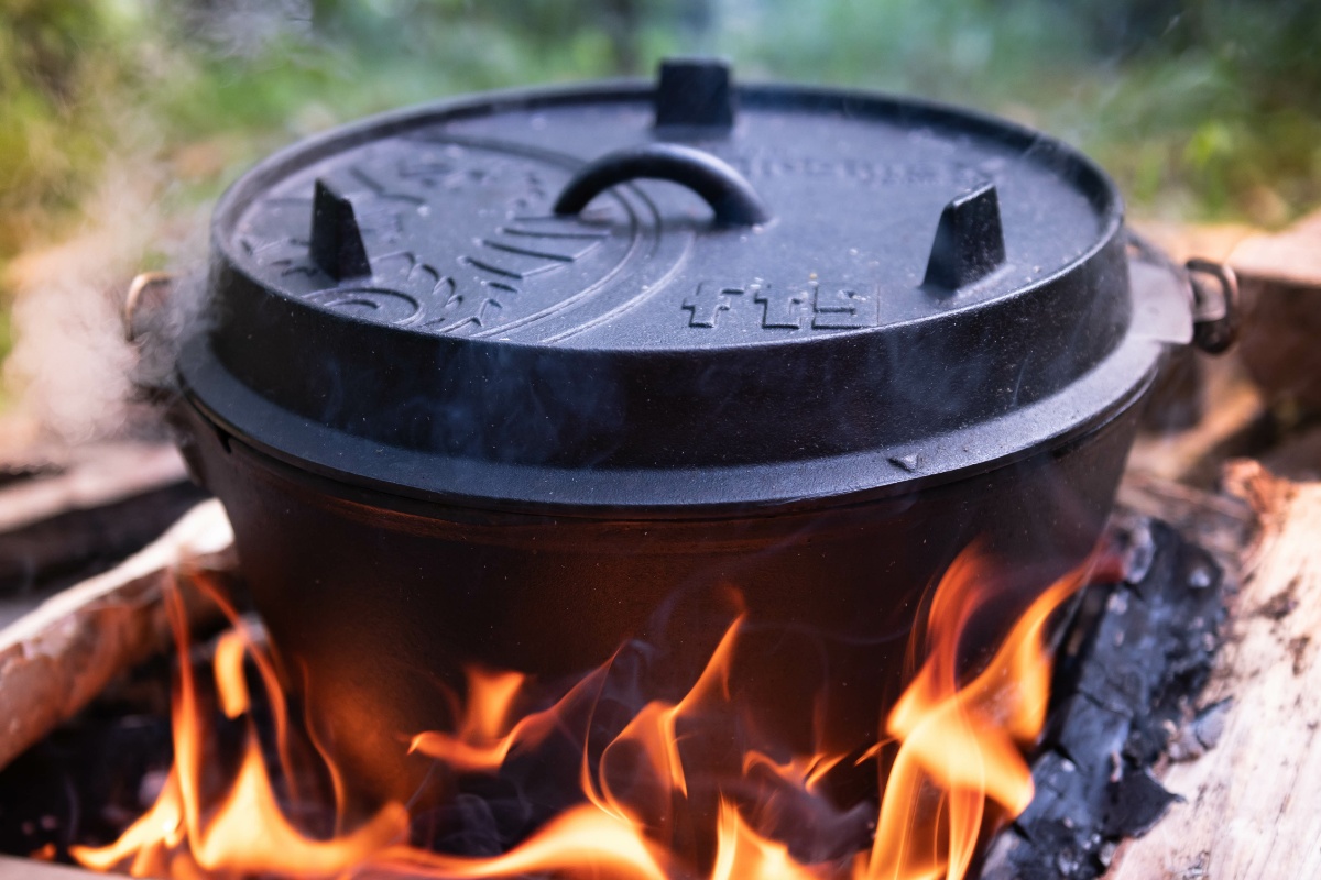 Dampfender Dutch Oven auf von Holzkohle gespeister offener Flamme.