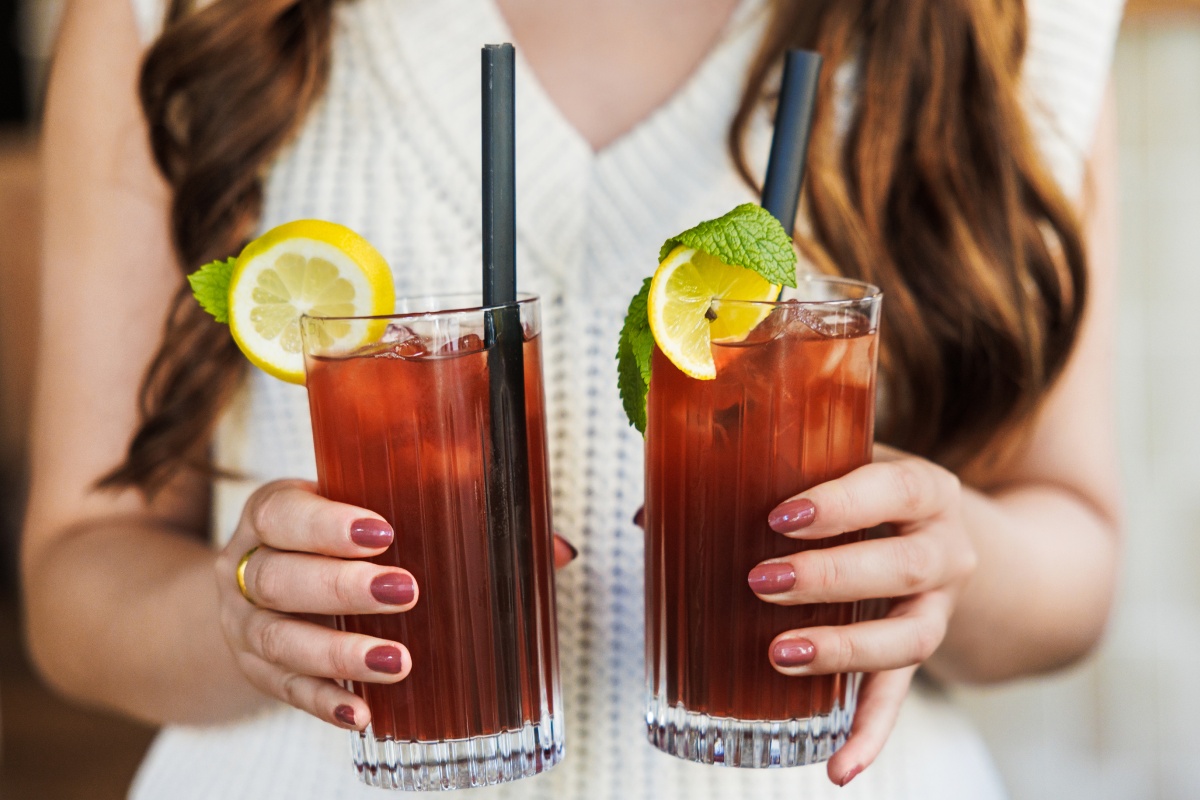 Eine Frau hält zwei Gläser Eistee in den Händen.