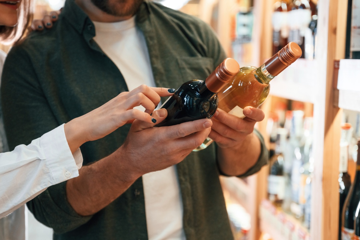 Eine Frau und Mann lesen Etiketten auf Weinflaschen.