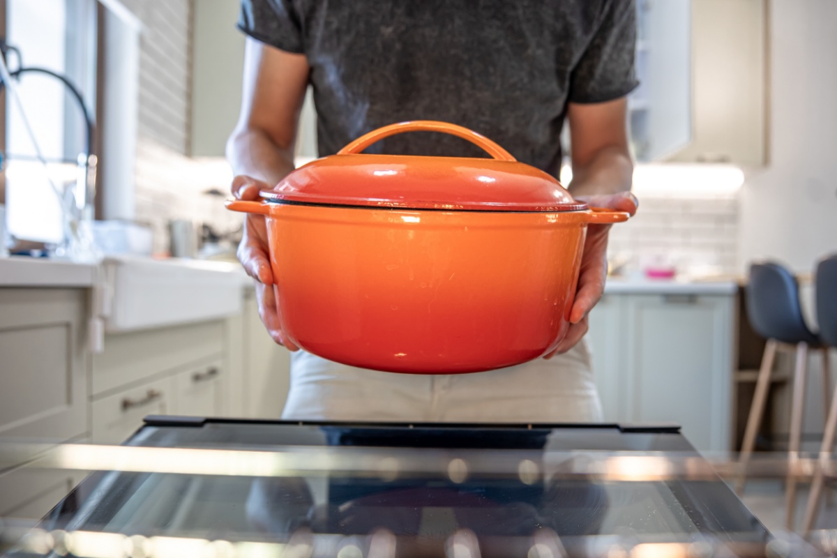 Eine Person hält einen roten Schmortopf..
