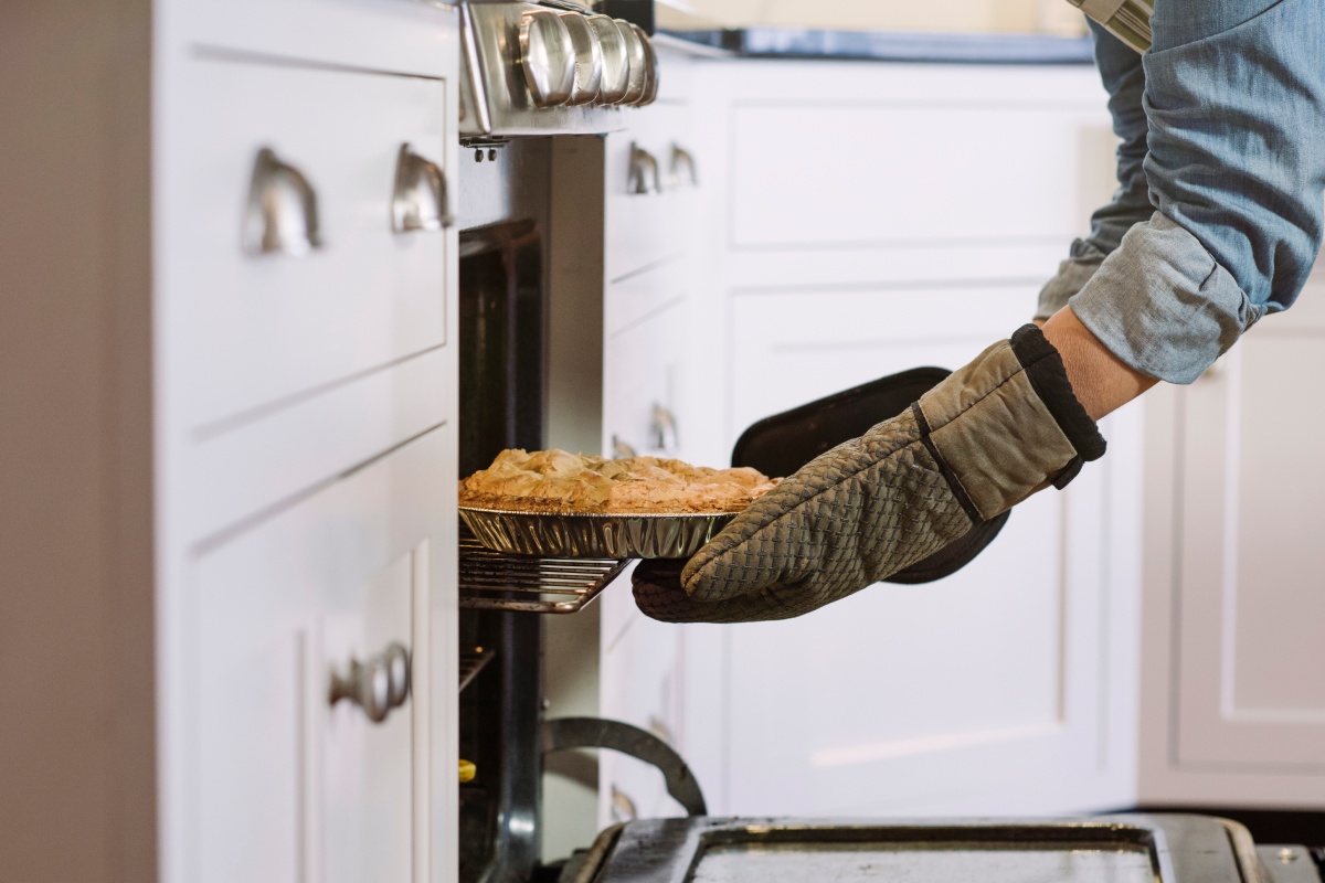 Eine Person holt einen frisch gebackenen glutenfreien Kuchen aus dem Ofen.