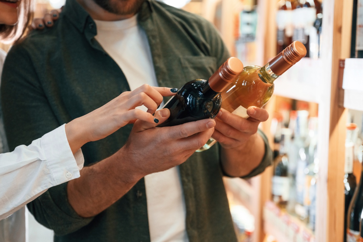 Eine Frau und Mann lesen Etiketten auf Weinflaschen.