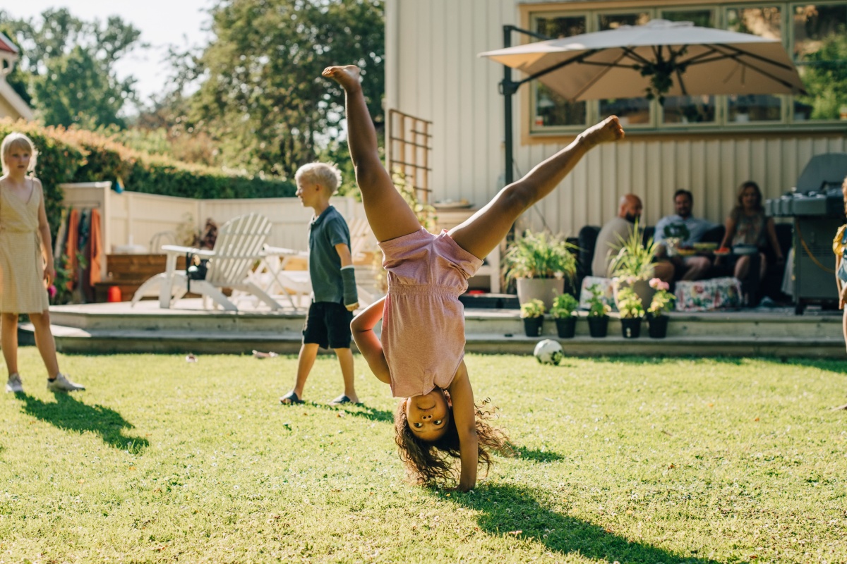 Ein Kind macht einen Handstand beim Spielen im Garten.