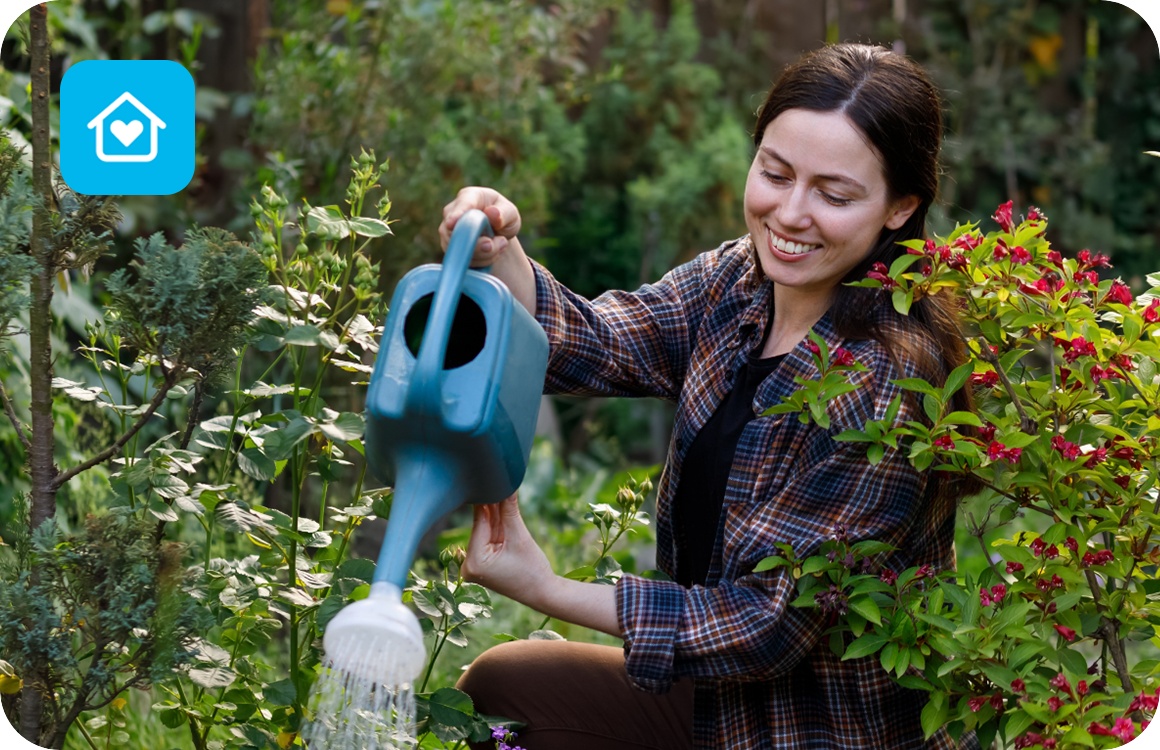 Frau gießt ihre Blumen im Garten.