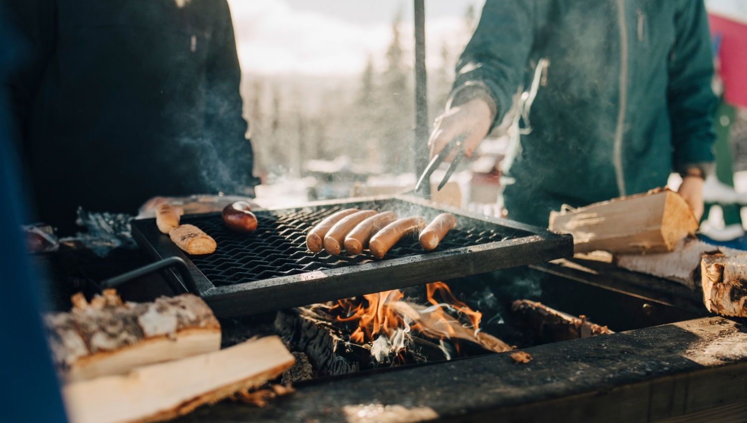 Grill mit bratenden Würsten über offenem Feuer. im Winter. 