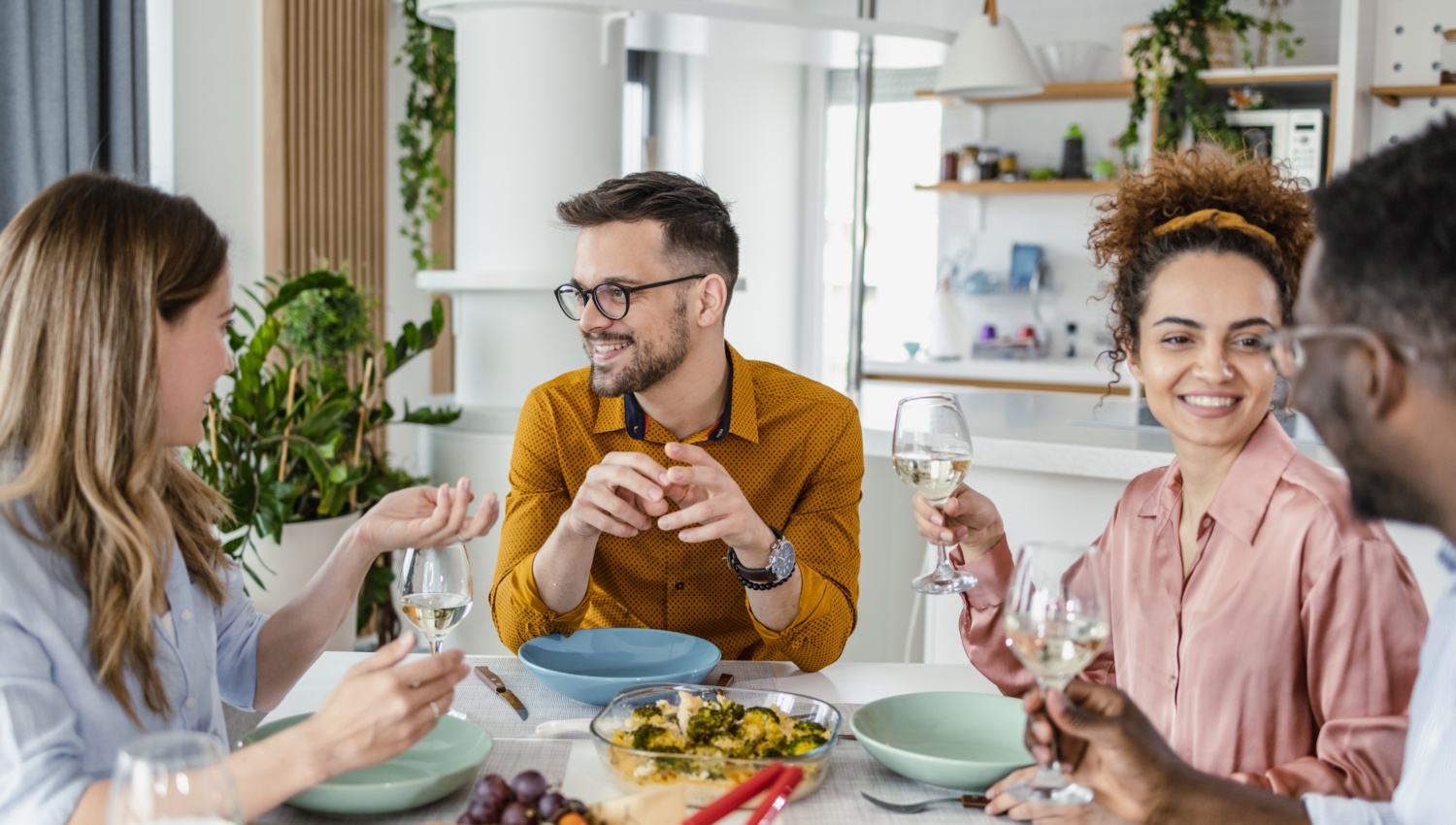 Gruppe von Gästen genießt ein gemeinsames Essen und Wein am gedeckten Tisch.