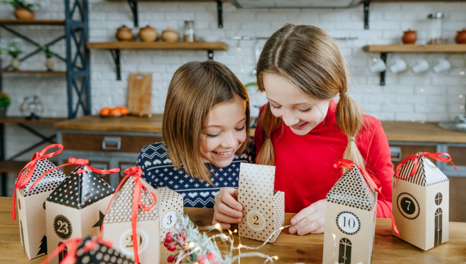 Zwei Mädchen öffnen fröhlich ein Türchen eines selbst befüllten Adventskalenders