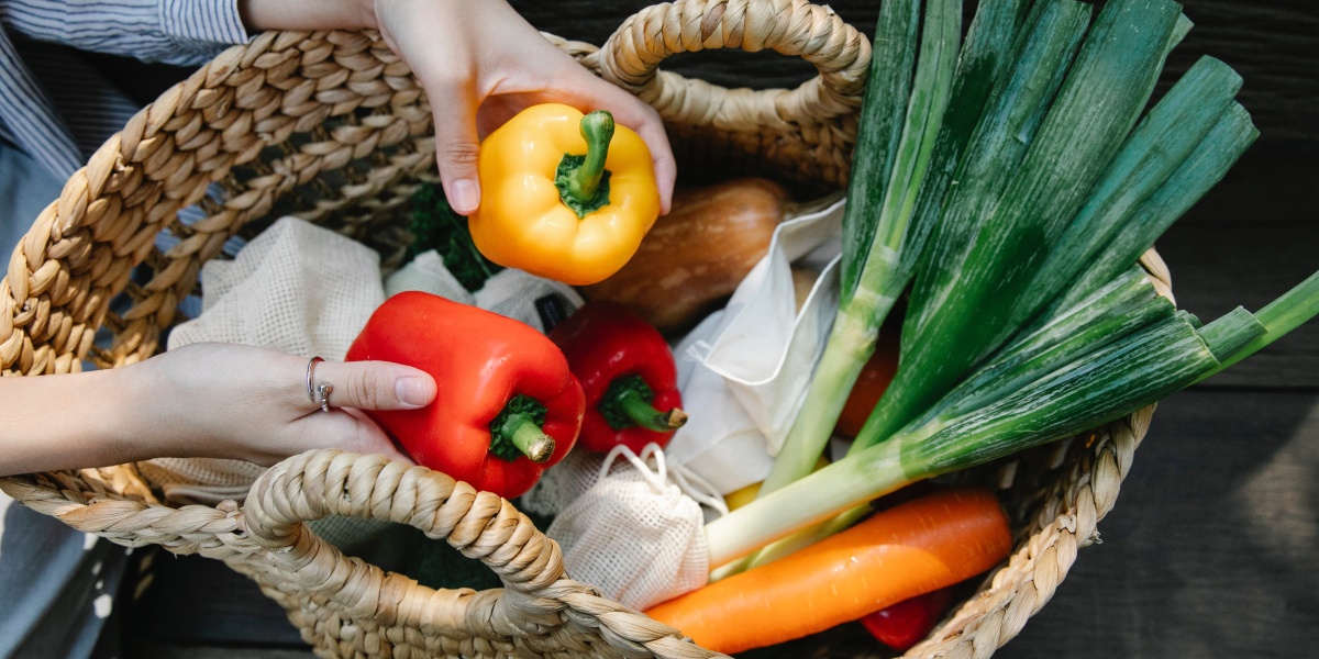 Hände nehmen Paprikas aus Korb mit Bio-Gemüse