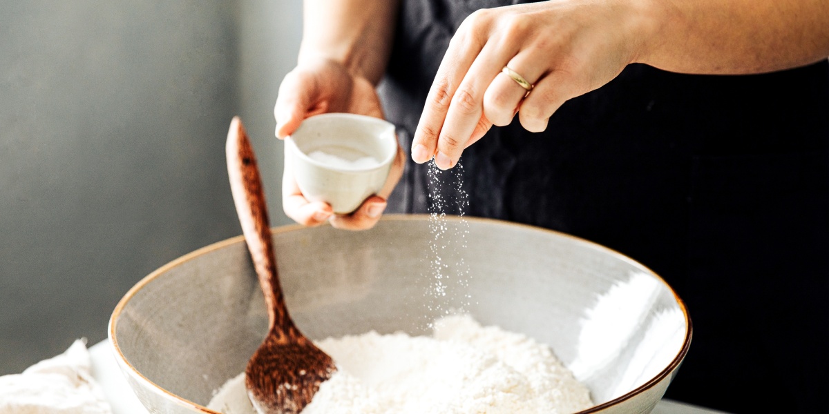 Eine Person streut eine Prise Salz in einen Teig.