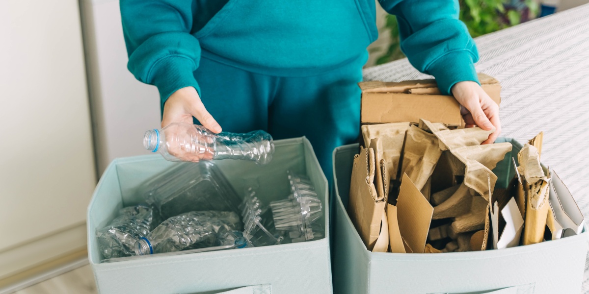 Eine Person sortiert Plastikflaschen und Papiermüll.