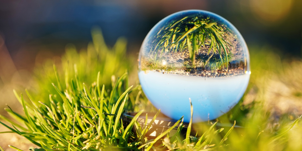 Ein Wassertropfen liegt auf ein paar kleinen Grashalmen.