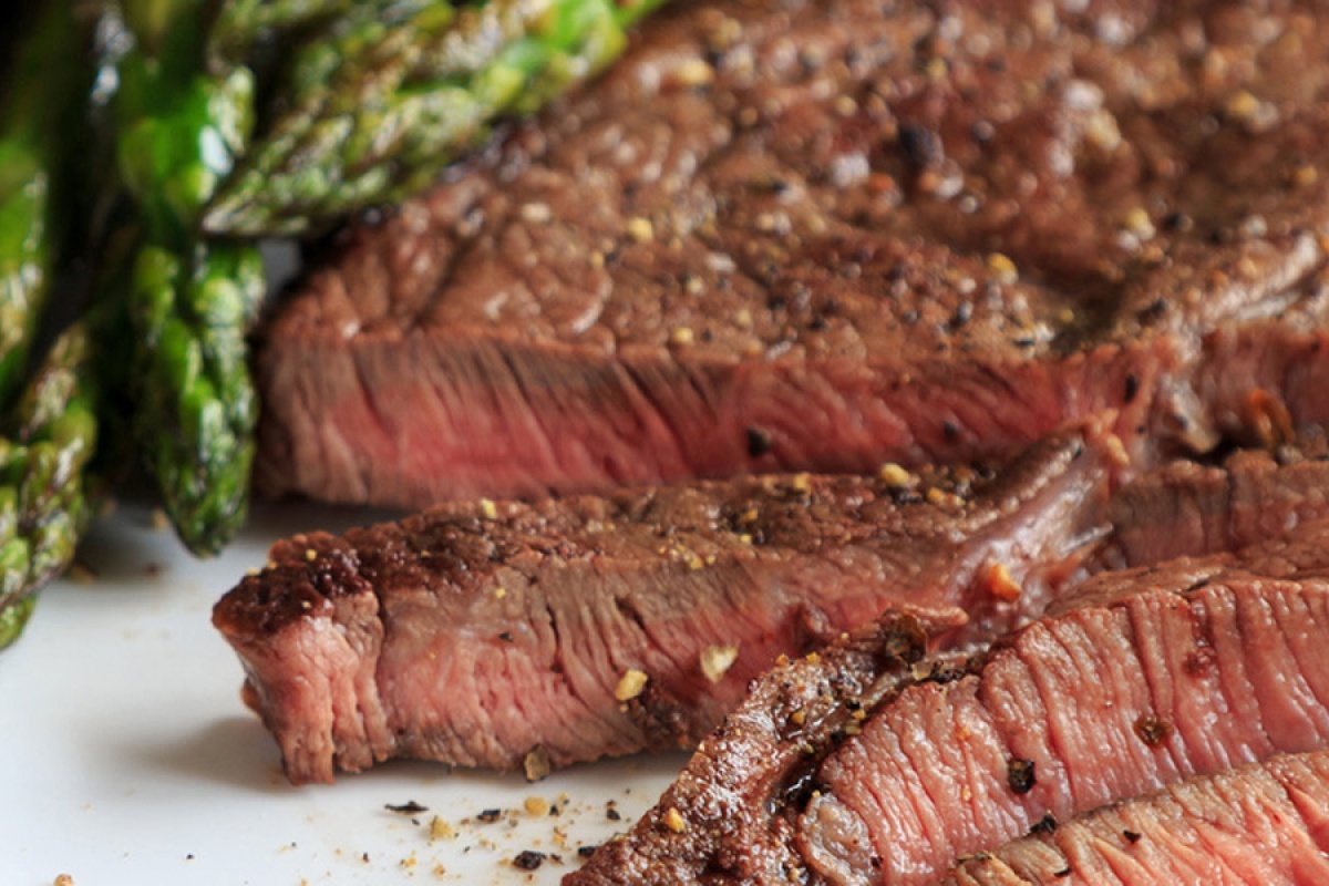 Saftig gebratenes Steak in Scheiben geschnitten, serviert mit gegrilltem Spargel.