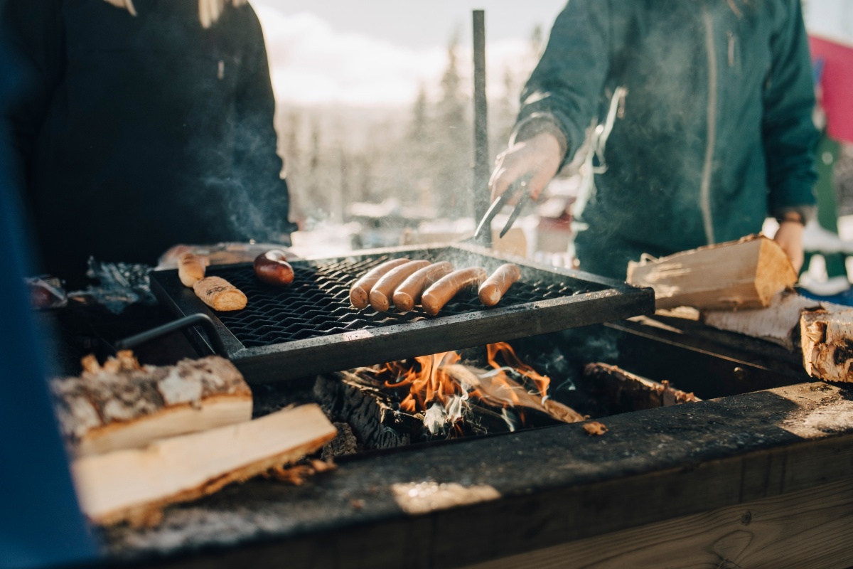 Grill mit bratenden Würsten über offenem Feuer. im Winter.