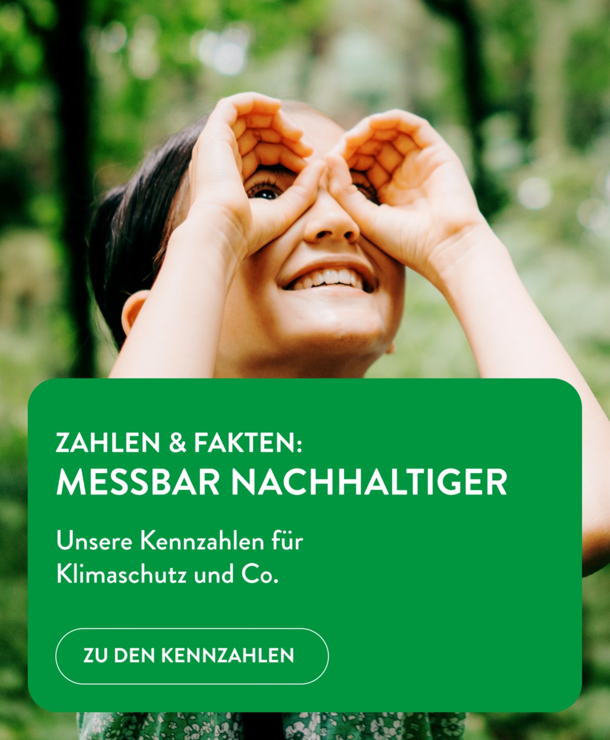 Ein Kind hält seine Hände wie ein Fernglas vor die Augen und betrachtet die Bäume im Wald.