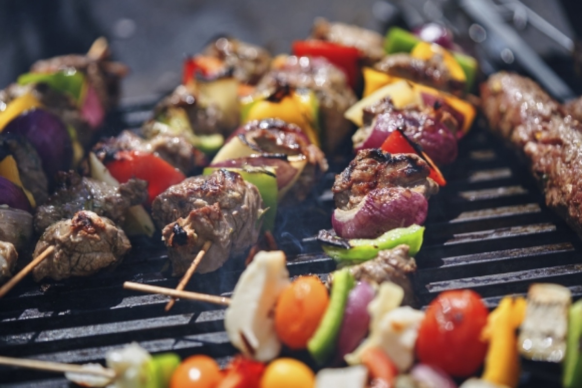 Gegrillte Fleisch- und Gemüsespieße mit Paprika, Zwiebeln und Tomaten auf einem heißen Grill.