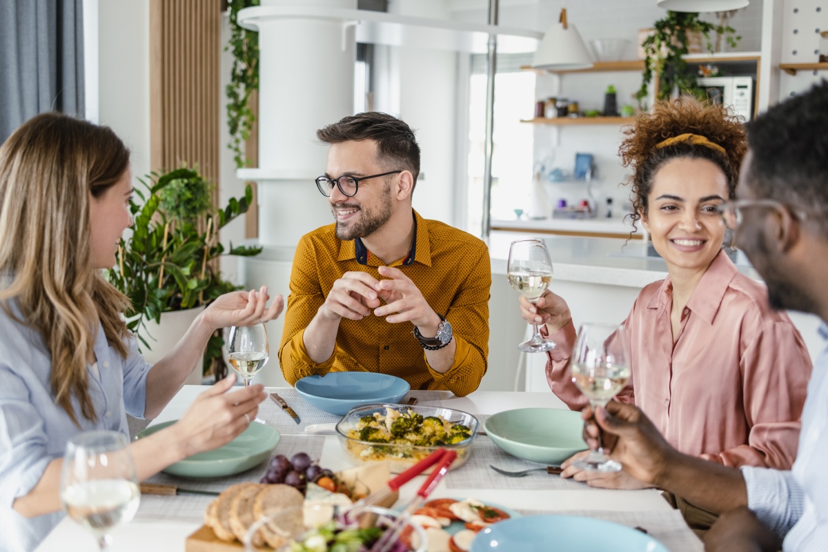 Gruppe von Freunden genießt ein gemeinsames Essen und Wein am gedeckten Tisch.