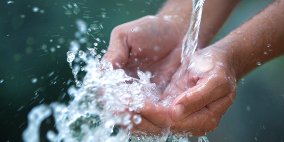 Eine Person hält ihre Hände unter einen Wasserstrahl.