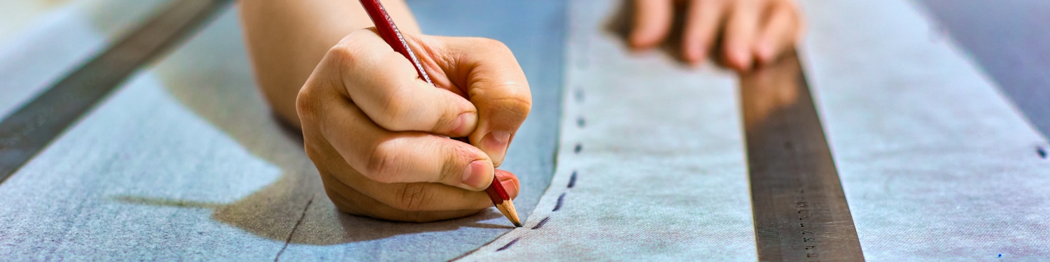 Eine Hand zeichent eine Naht auf einem Stück Stoff auf