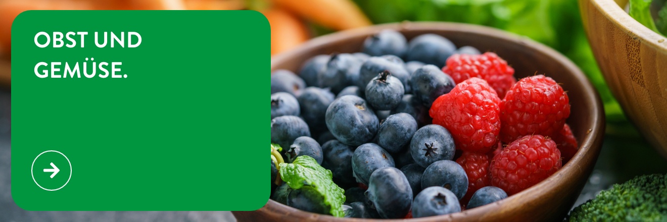 Eine Holzschüssel ist gefüllt mit Blaubeeren und Himbeeren.