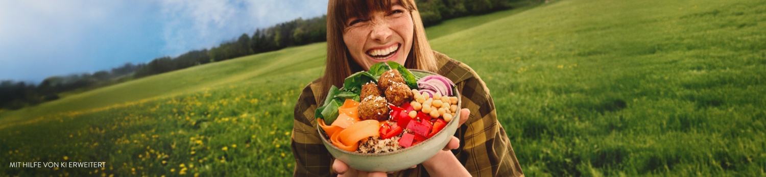 Eine Frau mit einer Falafel-Bowl steht auf der grünen Wiese.