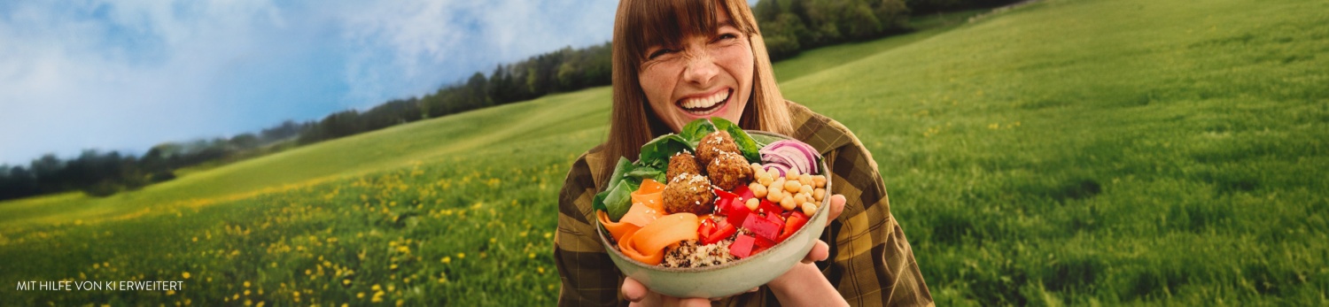 Eine Frau mit einer Falafel-Bowl steht auf der grünen Wiese.