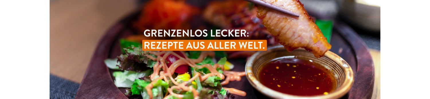 Gegrilltes Fleischstück in Stäbchen über einer Schale mit Soße, daneben frischer Salat mit Dressing, Nahaufnahme.