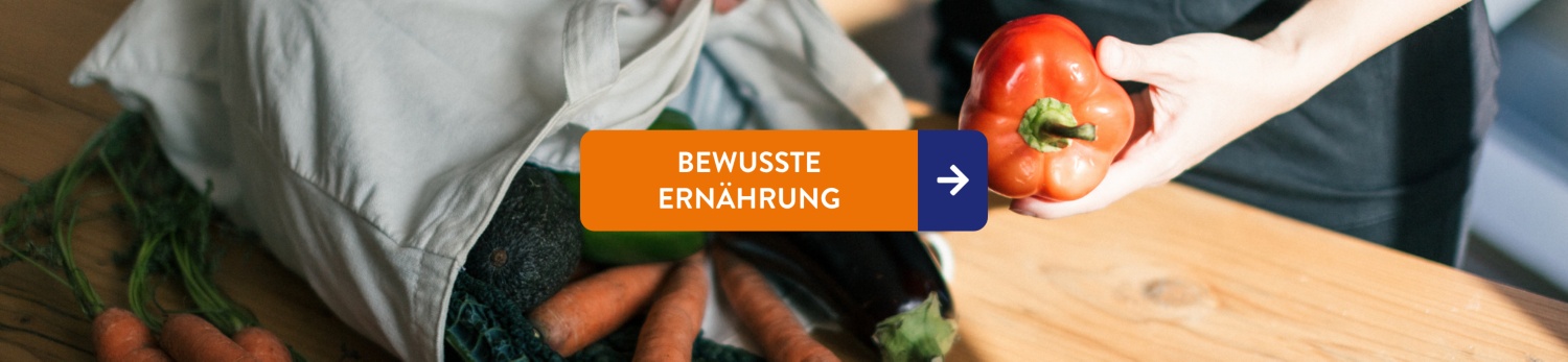 Eine Hand packt eine Paprika ins einen Jutebeutel voll Gemüse.