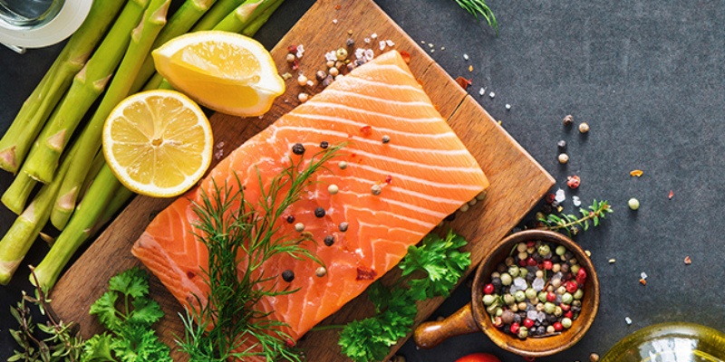 Losos, šparglji, limone in začimbe na leseni deski