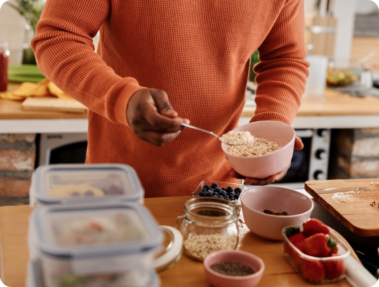 Eine Person bereitet ein Müsli aus Haferflocken und frischen Beeren zu.