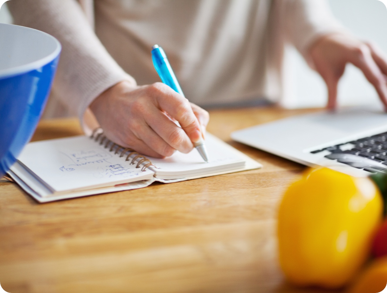 Person schreibt eine Einkaufsliste in ein Notizbuch.