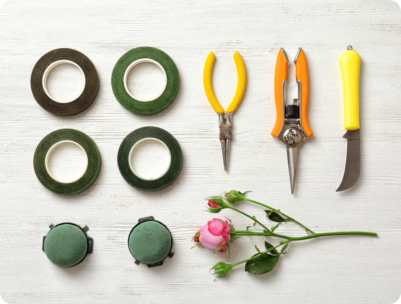 Klebeband, Schere, Messer und Steckschaum liegen bereit auf einer Tischplatte.