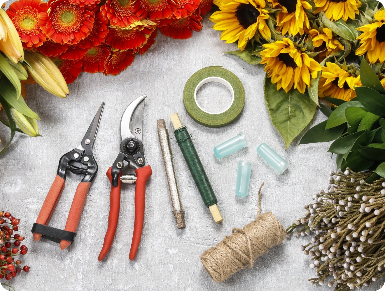 Gartenschere, Draht, Jurteband, Klebeband liegen it frischen Blumen auf einem Tisch.