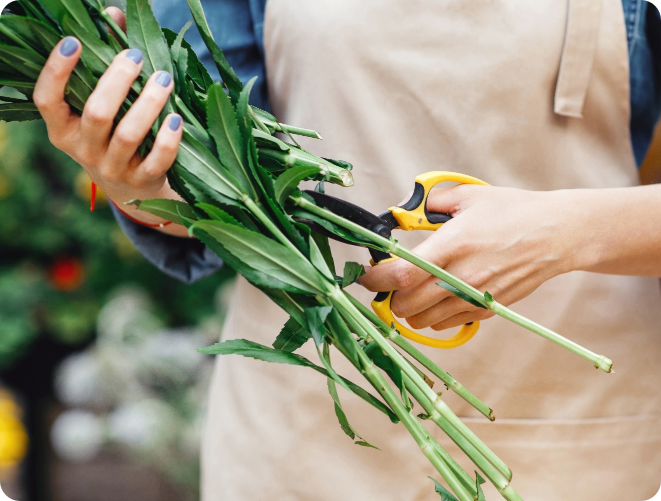 Floristin schneidet das Grün kurz für den Strauß.