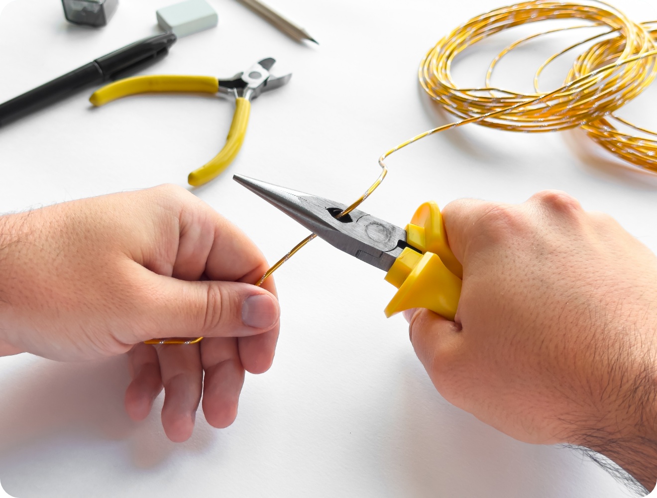 Person schneidet gelben Basteldraht.