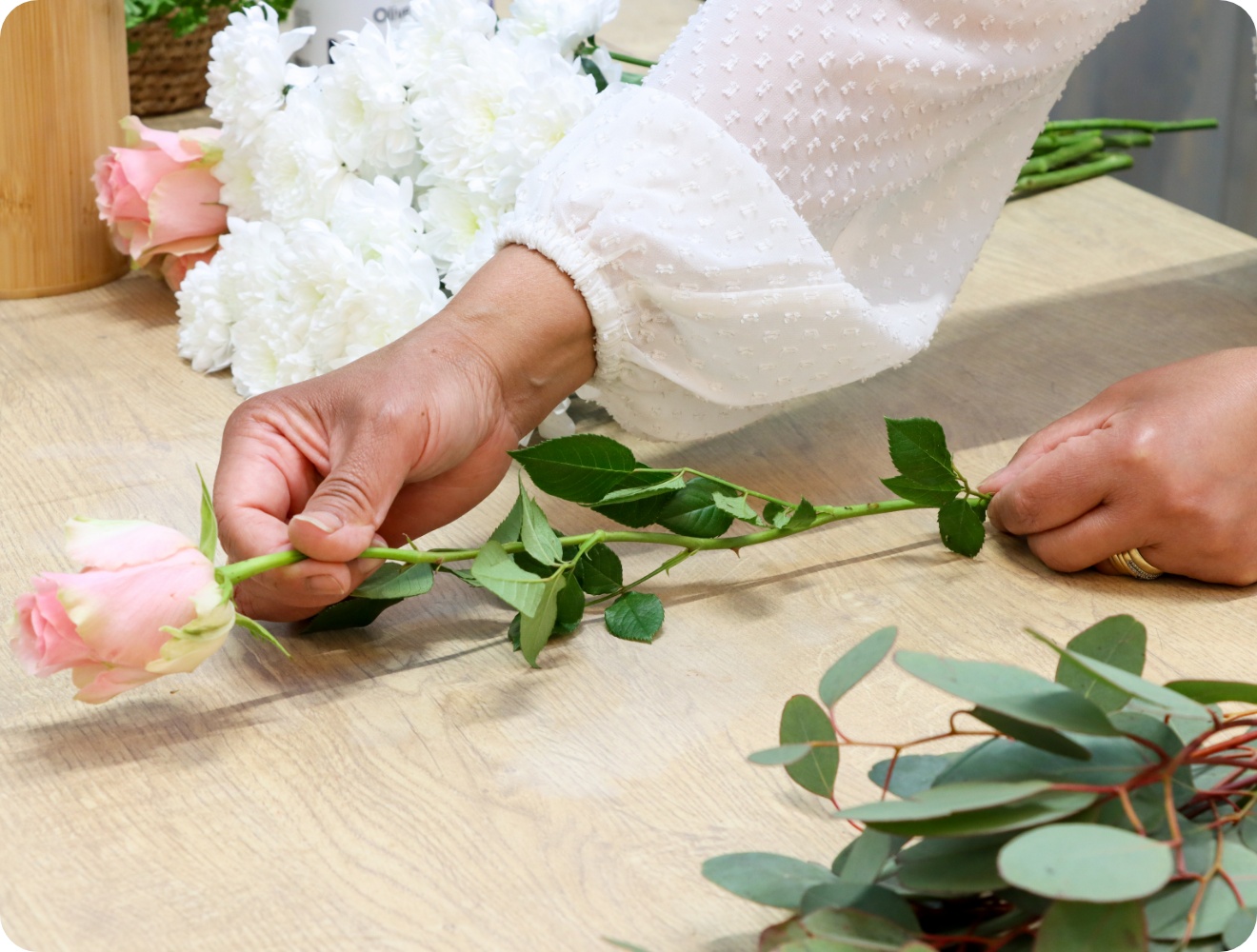 Person legt einen Rosenstiel vor sich auf die Tischplatte.