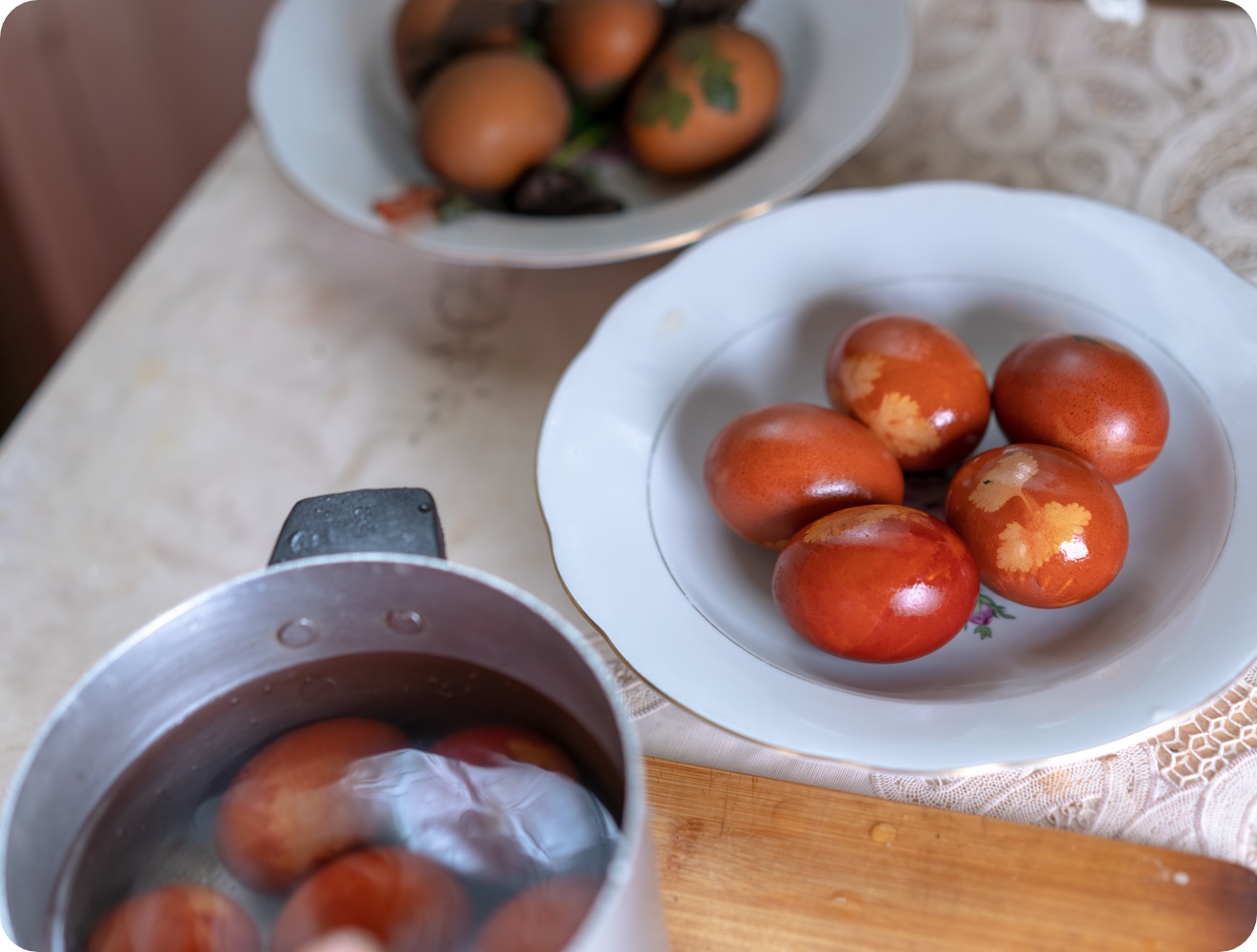 Braun-rot gefärbte Ostereier mit Blattmustern verziert auf einem Teller.