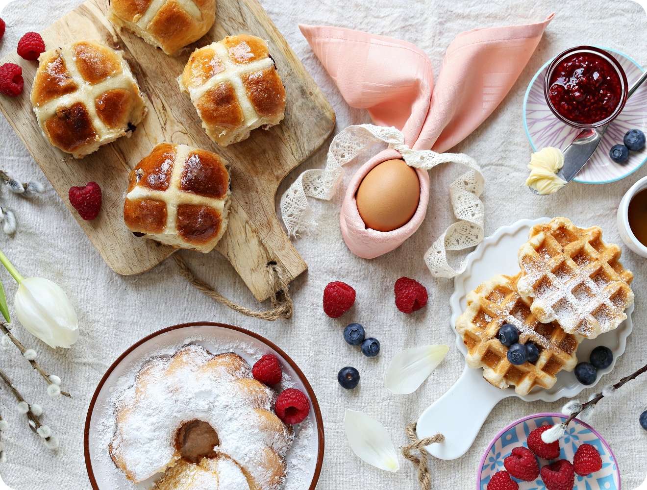 Kuchen, Waffeln, Eier und süßes Ostergebäck stehen auf einem Tisch für den Osterbrunch bereit.