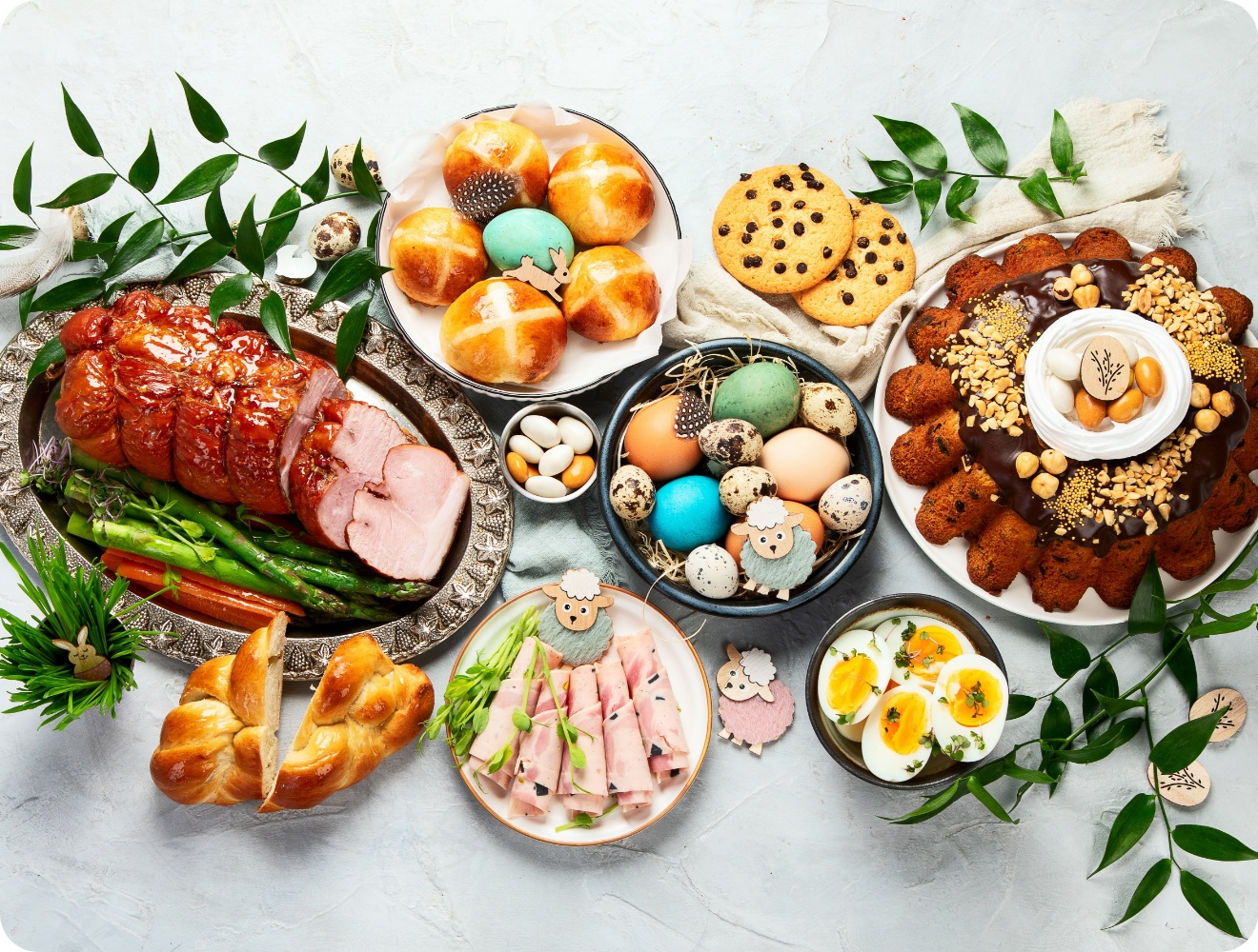 Osterbrunch mit glasiertem Schinken, bunt gefärbten Eiern, Hefezopf, Kuchen, Brötchen, Schinkenröllchen und Keksen.