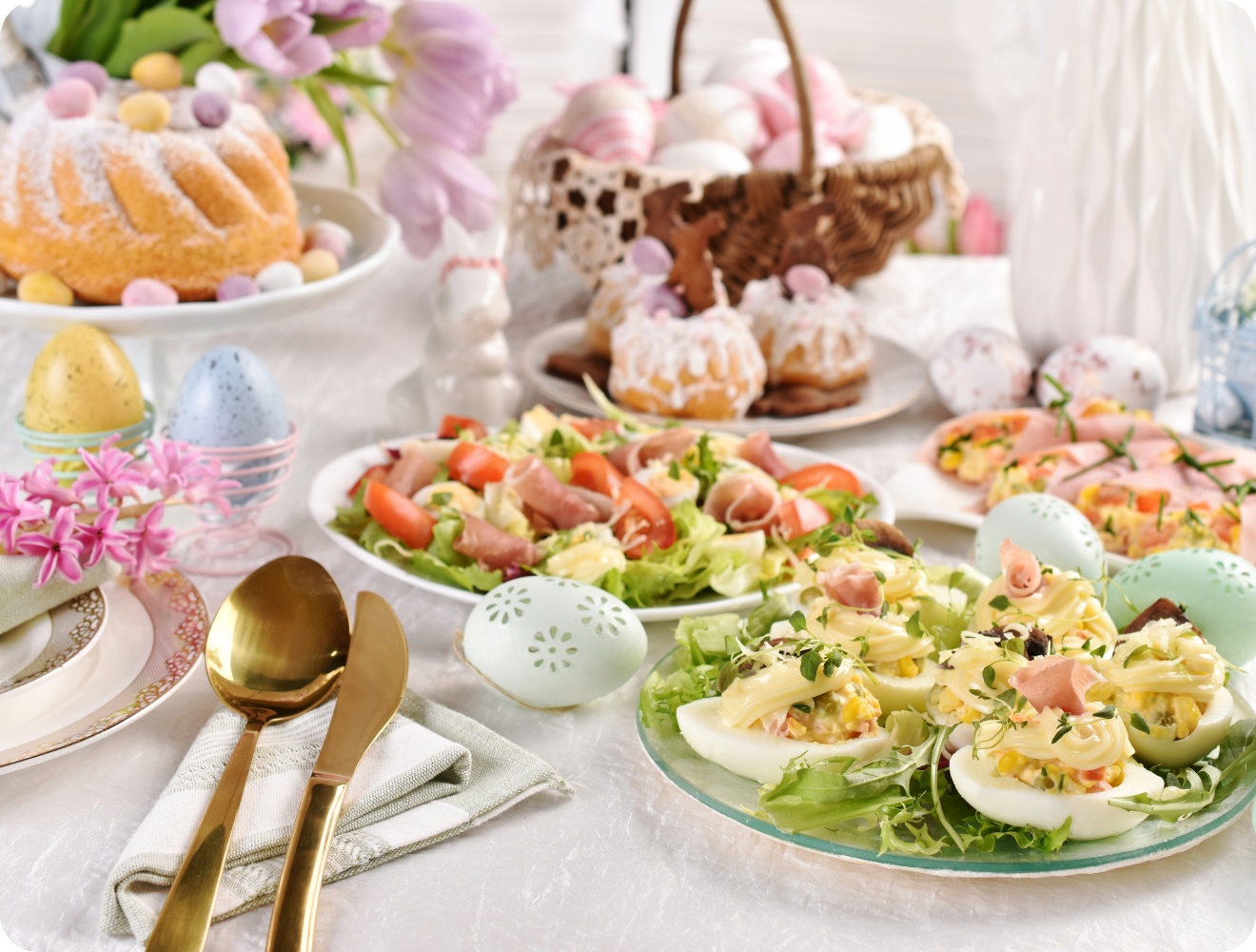 Osterbrunch mit gefüllten Eiern, Schinkensalat, Mini-Gugelhupf, Osterkuchen, bunten Eiern und Frühlingsdeko.