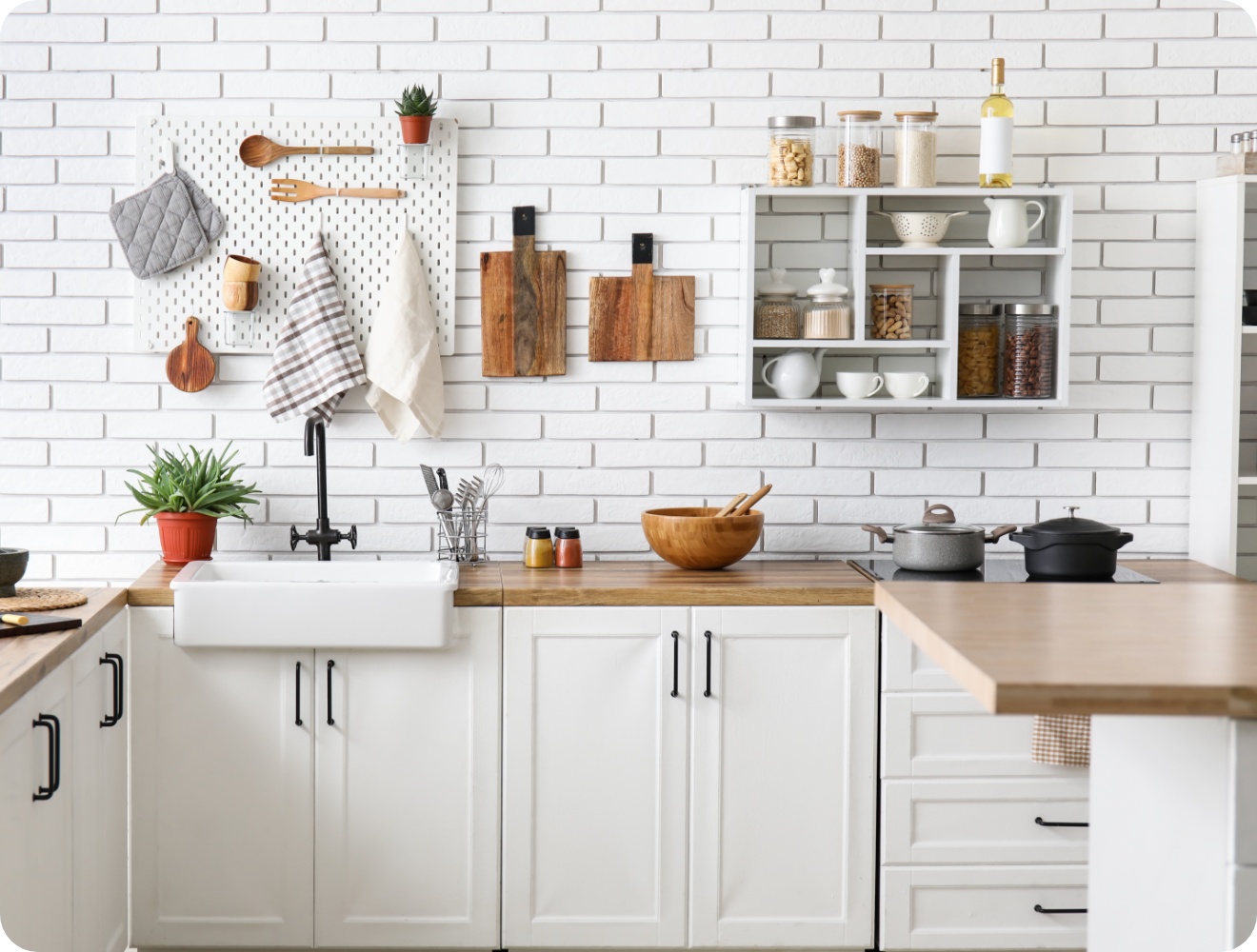 Helle Landhausküche mit weißen Schränken, Holzarbeitsplatte, offener Ablage und dekorativer Wandorganisation.
