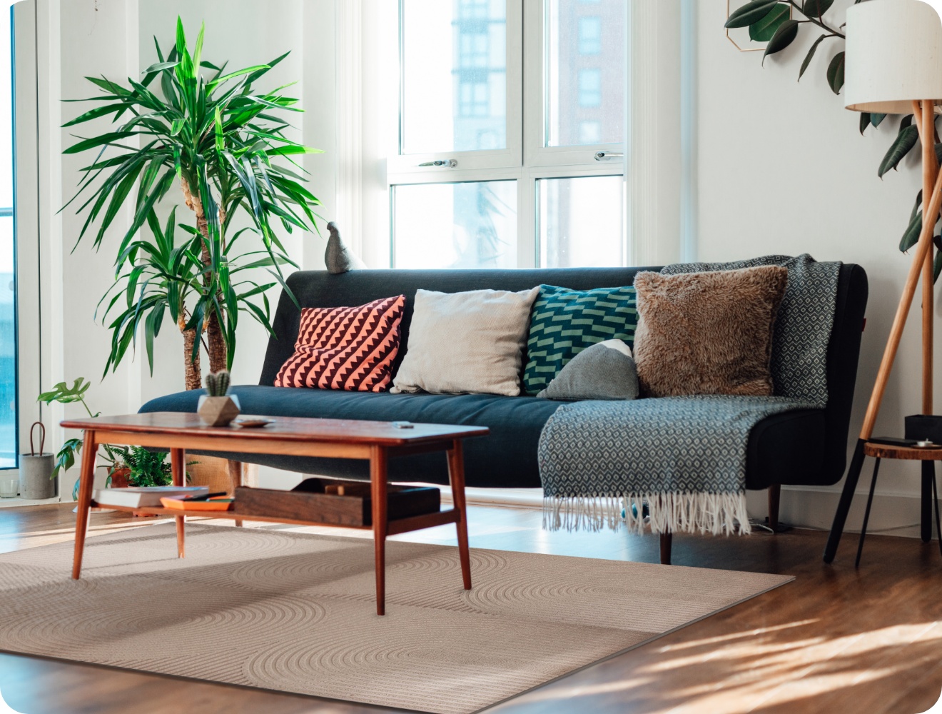 Modernes Wohnzimmer im Danish Design mit Pflanzen, Sofa mit Kissen, Holztisch, Stehlampe und mehreren ALDI Fußmatten als Teppich zusammengesetzt.