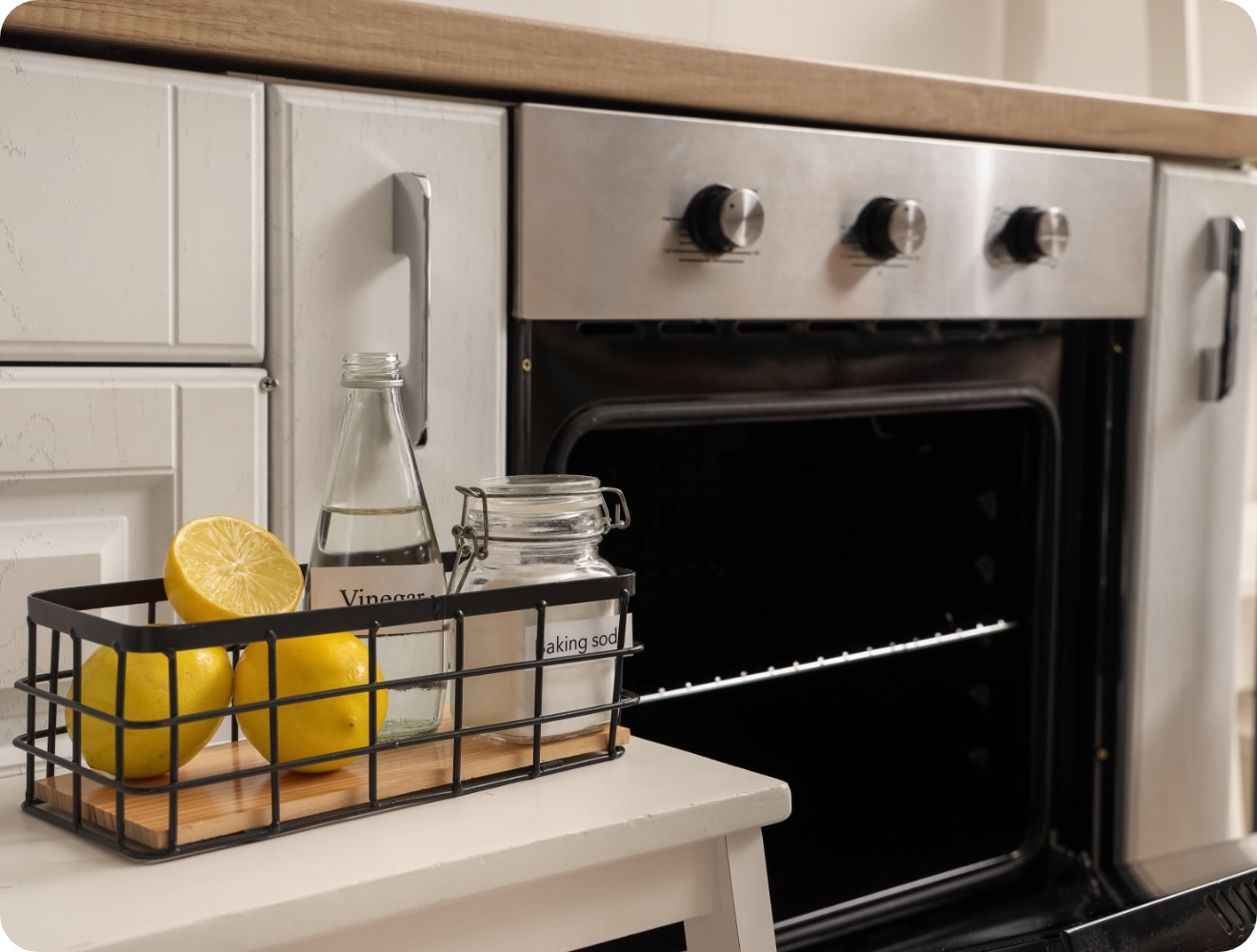 Blick auf einen geöffneten Backofen. Daneben stehen Behältnsse mit Essig, Soda und frische Zitronen .
