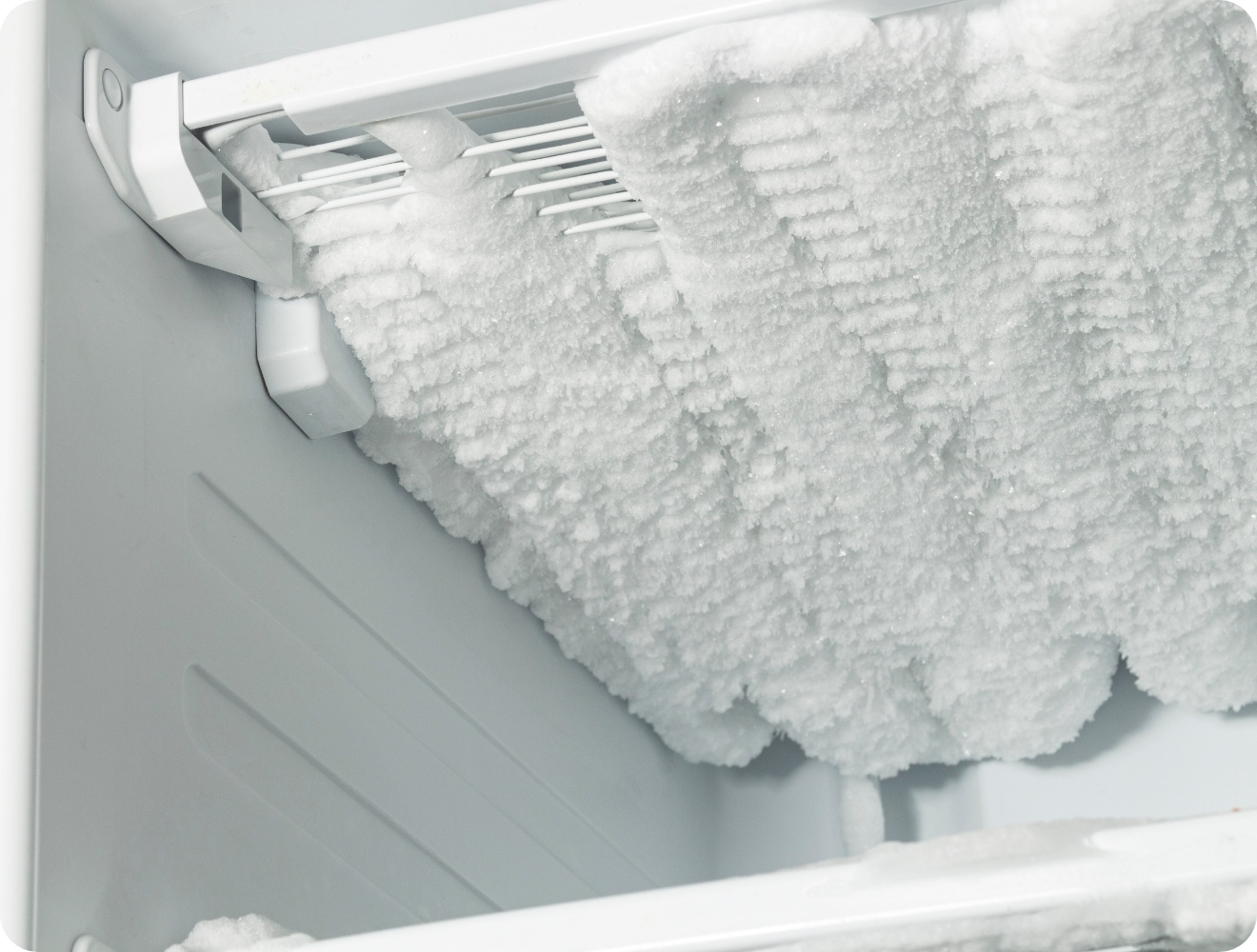Stark vereister Gefrierschrank von innen mit dicker Eisschicht an den Kühlrippen und Wänden.